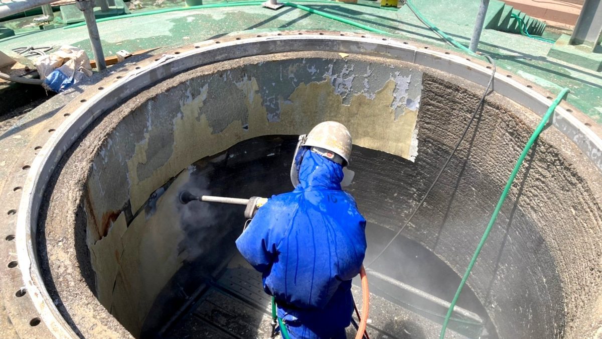 水処理施設の池内部で施工する様子。青いカッパは水を浴びる作業の必需品